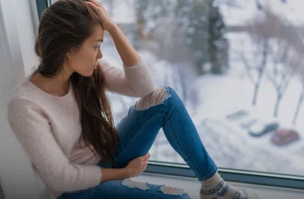 Mujer mirando a la ventana pensativa